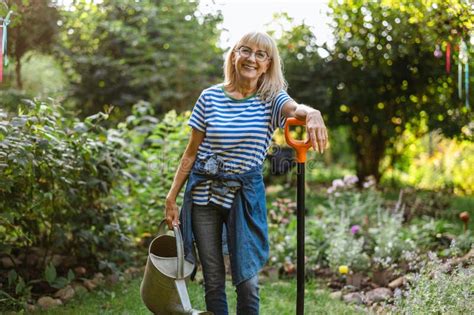 Mature Woman Watering Plants In Her Garden Stock Image Image Of Older Nature
