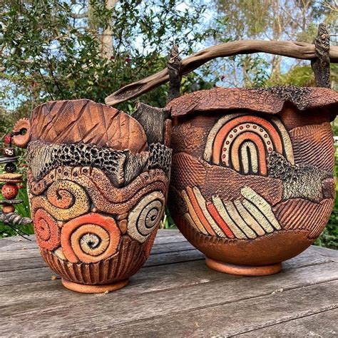 Two Clay Pots With Designs On Them Sitting On A Wooden Table In Front