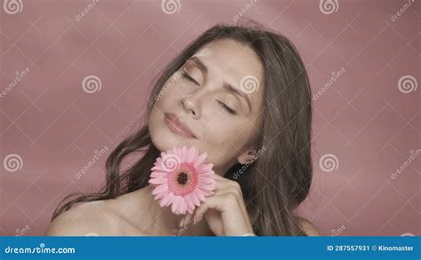 A Woman Runs A Gerbera Flower Across Her Perfect Skin Portrait Of A