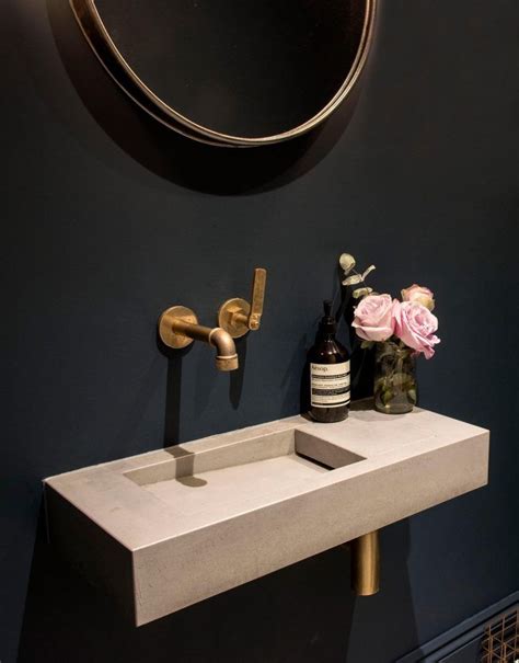 A White Sink Sitting Under A Mirror Next To A Wall Mounted Faucet In A