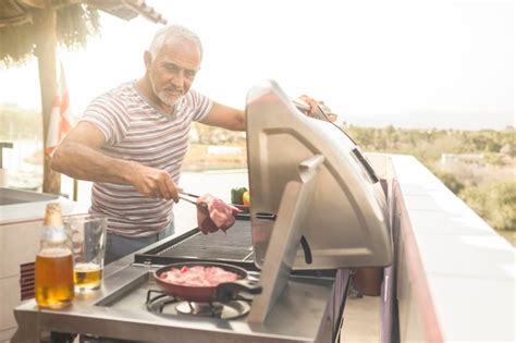 Premium Photo Mature Man Grilling Steaks On A Gas Grill On His