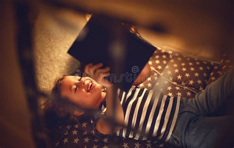 Happy Child Girl Laughing And Reading Book In Dark In Tent At Ho Stock