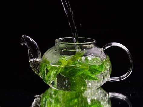 Premium Photo Pouring Hot Water Into A Glass Teapot On A Black Background Green Mint Tea