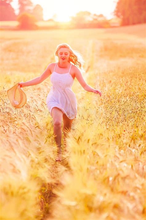 Jeune Fille Blonde Heureuse Dans La Robe Blanche Avec Du Th Courant De Chapeau De Paille Photo