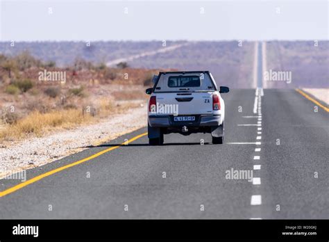 White Toyoya Hilux Pick Up Truck Driving Along A Very Straight And Long