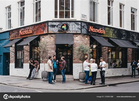 People Standing Outside Nandos Restaurant In Soho London Uk Stock