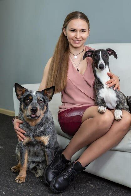 Une Jolie Fille Blonde Est Assise Sur Le Canapé à Côté Des Chiens De La Race Guérisseur Et