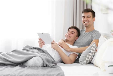 Premium Photo Happy Gay Couple Lying On Bed With Tablet At Home
