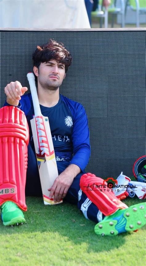 A Man Sitting On The Ground Holding A Cricket Bat