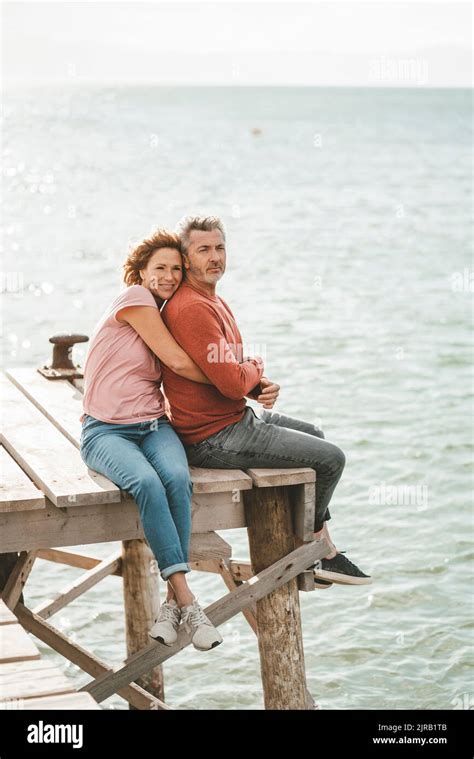 Smiling Mature Woman Hugging Man Sitting On Jetty Stock Photo Alamy
