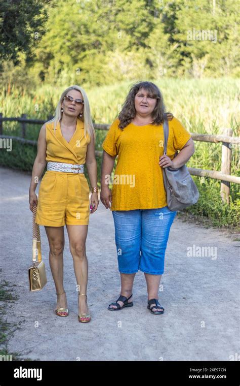 This Image Beautifully Captures Two Blonde Women Dressed In Yellow Enjoying A Leisurely Stroll