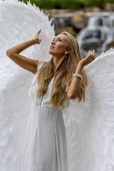A Lovely Blonde Model Poses Outdoors While Wearing White Handmade Wings For Halloween Stock