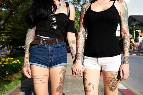 Premium Photo Tattooed Lesbian Couple Holding Hands In The Street In Summer