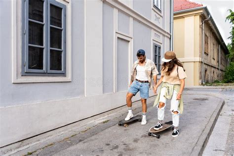 Tourists Couple Skateboarders Riding Skates. Happy Young Travelers