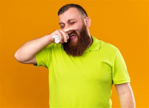 Homem barbudo insalubre em uma camisa pólo amarela se sentindo terrível