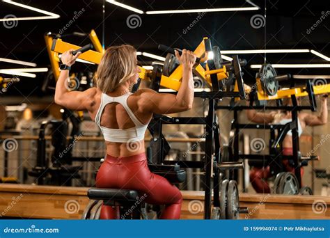Blonde Bodybuilder Woman Is Sitting And Doing Shoulder Exercises In