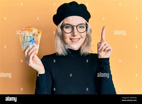 Jeune fille blonde portant des billets en francs suisses souriant avec une idée ou une question