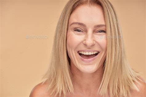 Portrait Of Attractive Happy Mature Lady Smiling At Camera While Posing Over Beige Background In