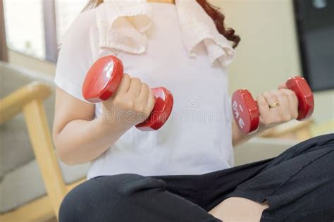 Cropped Shot Of Sporty Mature Woman With Red Dumbbells On Light Room