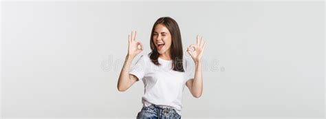 Satisfied Cheerful Brunette Girl Winking Sassy And Showing Okay Gesture In Approval Stock Image