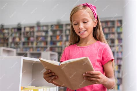 Маленькая девочка читает книгу в библиотеке | Бесплатно Фото