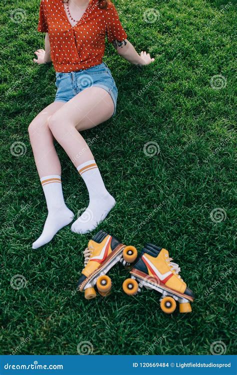 Cropped Shot Of Girl In Denim Shorts And Socks Resting On Grass Stock