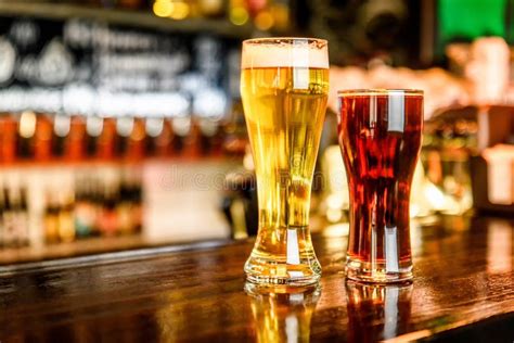 Verre De Bière Blonde Et Foncée Sur Un Bar Avec Le Fond De Bokeh Image stock Image du