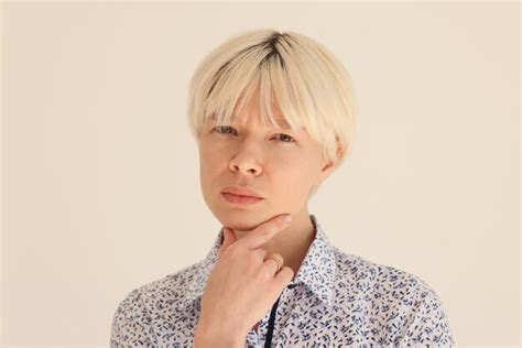 Premium Photo Pensive Woman With Dyed Blonde Hair Touches Chin With Fingers Looking In Camera