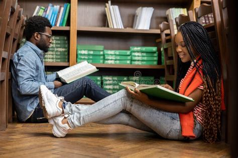 African American Students Reading Books While Sitting On The Floor In
