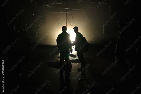 Silhouettes Of Explorers Inside The Tunnel Of An Old Abandoned Coal