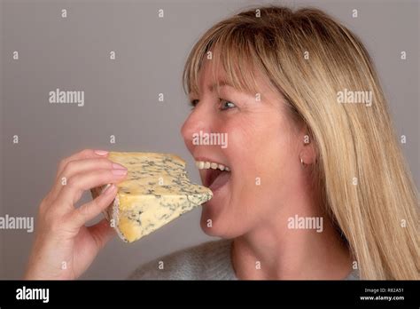 Blonde Woman Eating And Enjoying A Wedge Of Blue Cheese Stock Photo Alamy