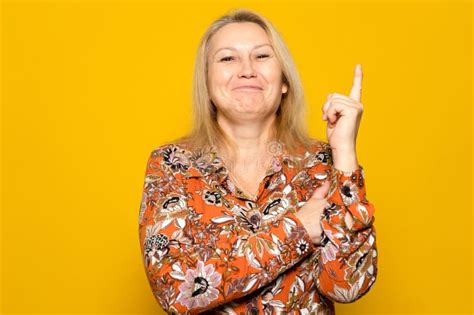 Caucasian Blonde Woman In A Patterned Dress Raising Her Index Finger Smiling She Had A Great