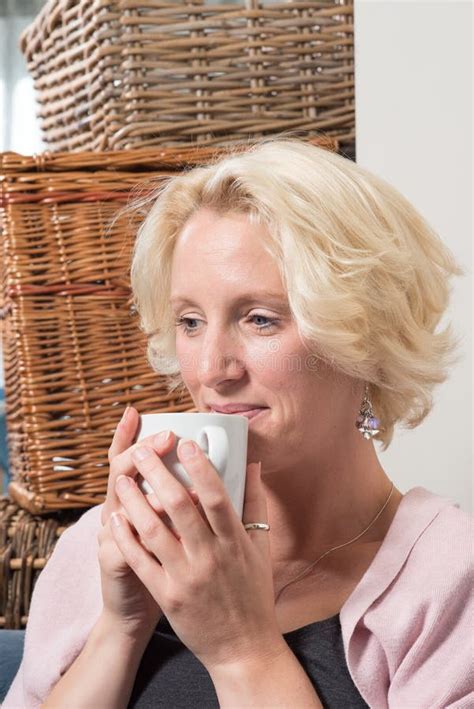 Sitting Blonde Woman Smiles With Satisfaction While Holding Hot Stock Image Image Of Sofa