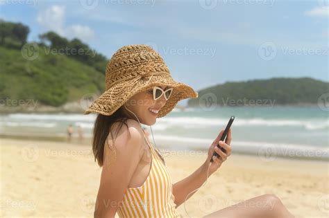 jeune belle femme en bikini écoutant de la musique et utilisant un