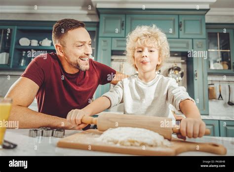 Curly Blonde Haired Son Rolling Out Pastry While Helping Father Stock Photo Alamy