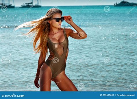 Portrait Of Beautiful Smiling Blonde Woman With Long Hair And Tanned Body Wearing Gold Swimsuit