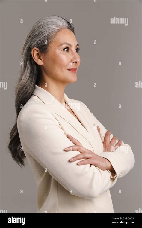 Mature Asian White Haired Woman Posing With Her Arms Crossed Isolated Over Grey Background Stock