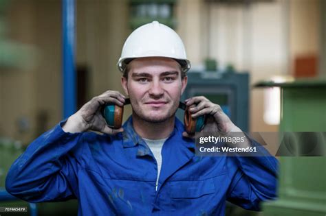 Portrait Of Worker With Helmet And Ear Muffs In Factory High Res Stock