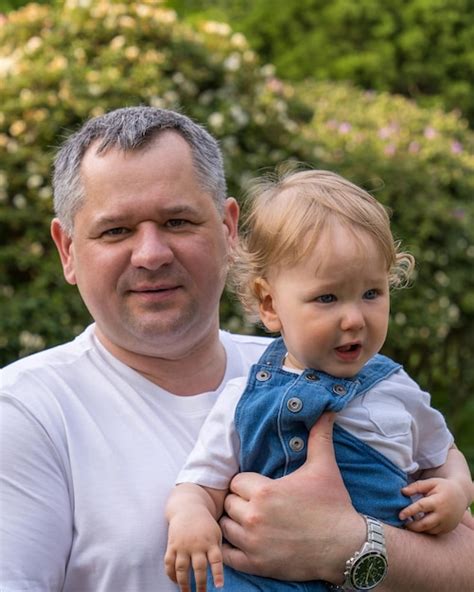 Padre feliz sostiene en sus brazos a un niño pequeño con cabello rubio