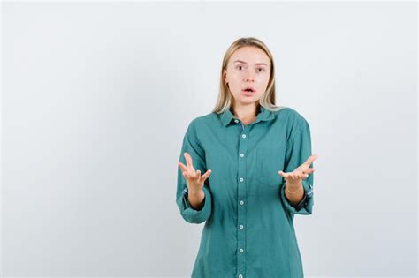 Fille blonde en chemisier vert s étendant les mains comme tenant quelque chose et à la surprise