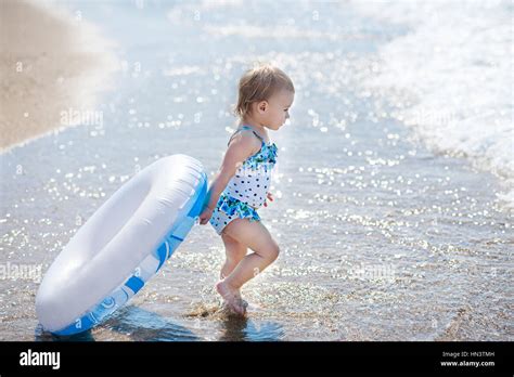 Kleinkind hübsches Mädchen gekleidet im Bikini stehen am tropischen Strand mit aufblasbaren