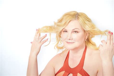 Middle Aged Blonde Woman Displaying Her Unkempt Hair Against A White Background Stock Photo