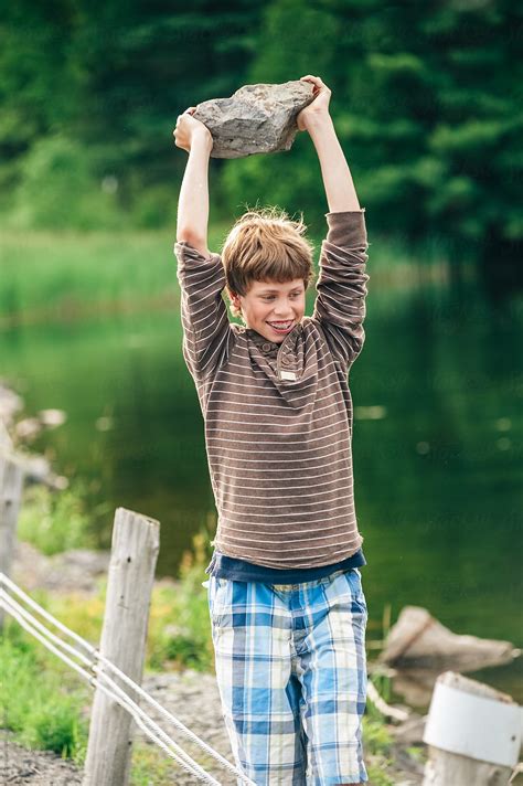 Boy Throwing Rocks At The Side Of The Road By Stocksy Contributor