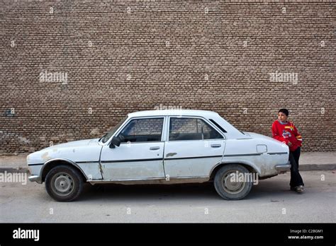 A young boy stands by an old Peugeot 504 car in the old city of UNESCO ...