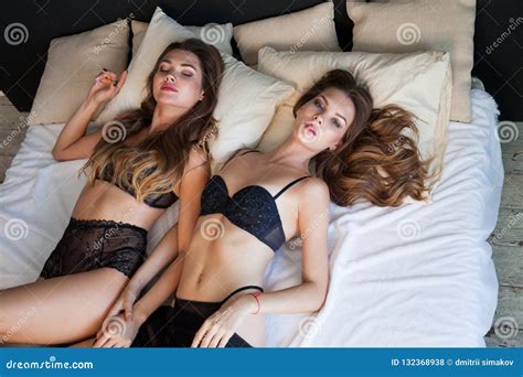 Two Beautiful Fashionable Woman In Lingerie Lying On A Bed In The