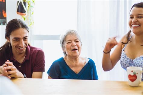 Abuela latina riéndose con sus nietos en el comedor en medio de una reunión familiar Foto Premium