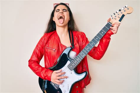 Una Adolescente De Brunette Que Toca Guitarra Eléctrica Y Se Pega La Lengua Feliz Con Expresión