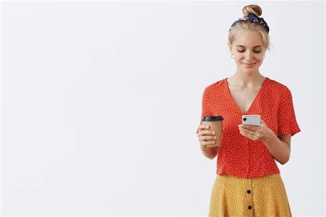 Belle élégante jeune fille blonde posant contre le mur blanc Photo Gratuite