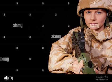 Female Soldier Holding An Sa80 Rifle Against A Black Background She