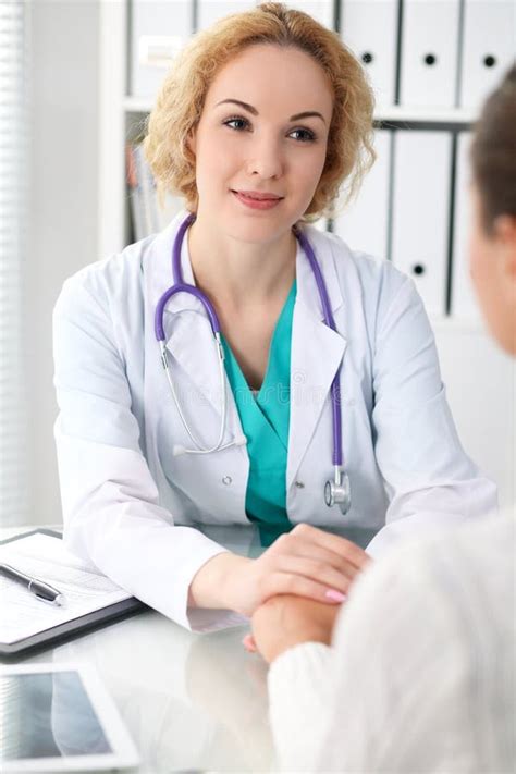 Happy Blonde Female Doctor Looking At Patient While Speaking To Her And Reassuring Medicine